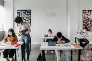 Students and teacher in masks in a classroom setting post-pandemic, focusing on safe learning.